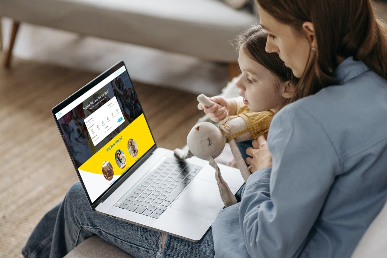 Customer retention: A mother with her young daughter sat on her lap browsing pet services on the Book Your Pet Marketplace.